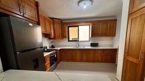 Eine Küche mit Holzausstattung, einem Kühlschrank, einem Herd, einer Mikrowelle und einem Fenster.