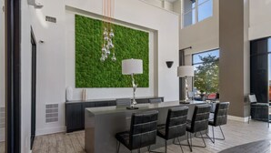 A modern kitchen with a green textured wall, a central island with bar stools, and pendant lighting. - Luxury Studio with Balcony and Makeup Room (Nashville)