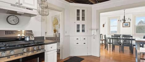 Una cocina con armarios blancos, una estufa de acero inoxidable y techo de madera.