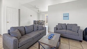 Ein Wohnzimmer mit zwei grauen Sofas, einem Holztisch und einem Deckenventilator.