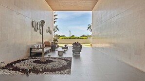 Un área lounge exterior moderna con un muro de piedra, un conjunto de asientos y vistas al exterior.