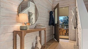 A wooden interior with a console table, a mirror, and a coat rack.