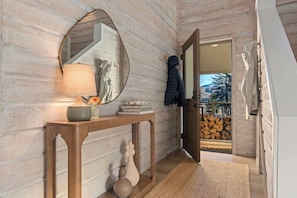 A wooden interior with a console table, a mirror, and a coat rack.