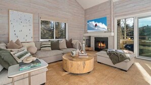 A modern living room with a large TV, a fireplace, and a cozy sofa.