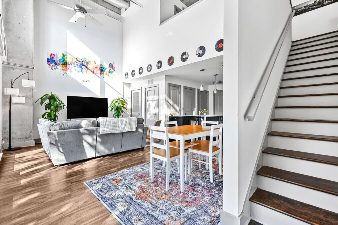Ein modernes Wohnzimmer mit grauem Sofa, einem Holzespeisetisch und einem gemusterten Teppich.