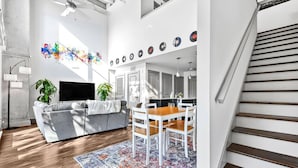 Ein modernes Wohnzimmer mit grauem Sofa, einem Holzespeisetisch und einem gemusterten Teppich.