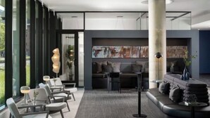 Eine moderne Lobby mit einer Couch, Sesseln und einem großen abstrakten Gemälde.