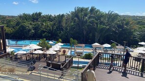 Ein Resort-Poolbereich mit mehreren Schwimmbecken, Sonnenschirmen und Liegestühlen.