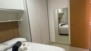 Hotellihuone, jossa on sänky, vaatekaappi, peili ja ovi.