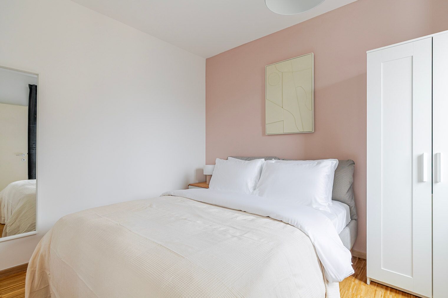 Une chambre à coucher comprenant un lit, une armoire, une table de chevet et une œuvre d’art abstraite accrochée au mur.