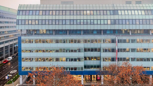 Un immeuble moderne à plusieurs étages, doté de grandes fenêtres et d’un toit plat.