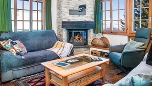Ein gemütliches Wohnzimmer mit Kamin, einer Couch, einem Couchtisch und einem Sessel.