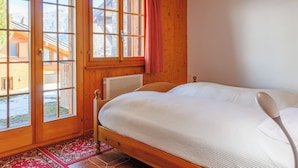 Ein Schlafzimmer mit Holzwänden, einem Bett, einem Heizkörper und Blick auf einen Berg durch große Fenster.