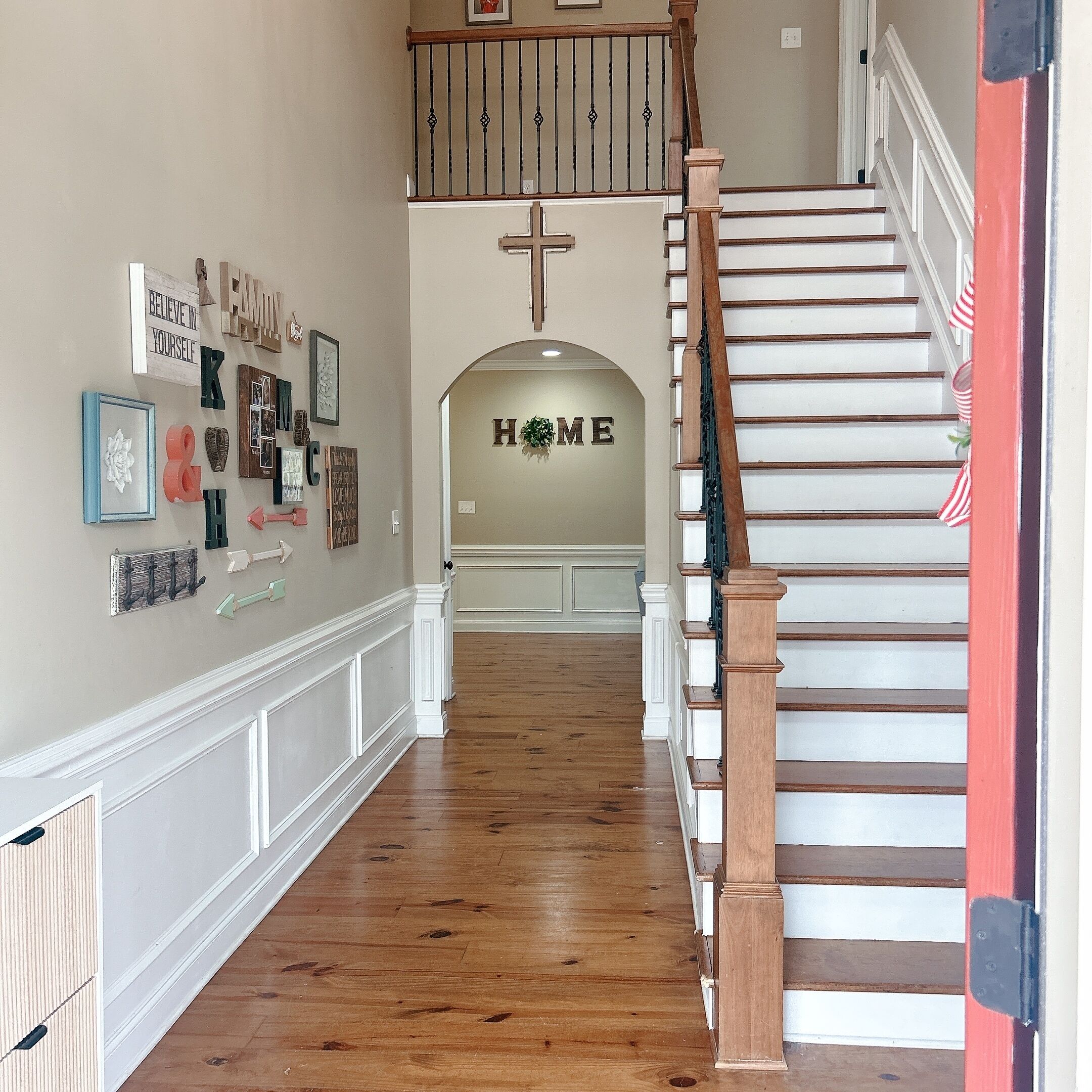 Un escalier avec des marches en bois et une rampe, menant à un palier où est affiché un panneau indiquant « MAISON ».