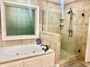 A bathroom with a bathtub, a glass-enclosed shower, and a vanity with a mirror. - Spacious & Charming 5-Bedroom Family Home in Quiet Evans Neighborhood. (Evans)