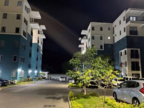 A nighttime view of a residential building with multiple floors, a parking area, and a well-lit entrance. - Charming 1 Bedroom Apartment Unit in the Heart of The City. (Kingston)