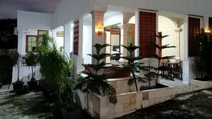 A modern building with a covered outdoor area, columns, and potted plants. - Pakemsari Resort Hotel (Pakem)