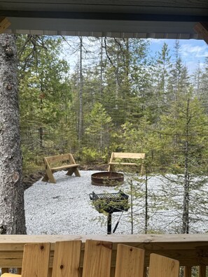 Eine Holzterrasse mit Bänken und Grillplatz, umgeben von Bäumen.