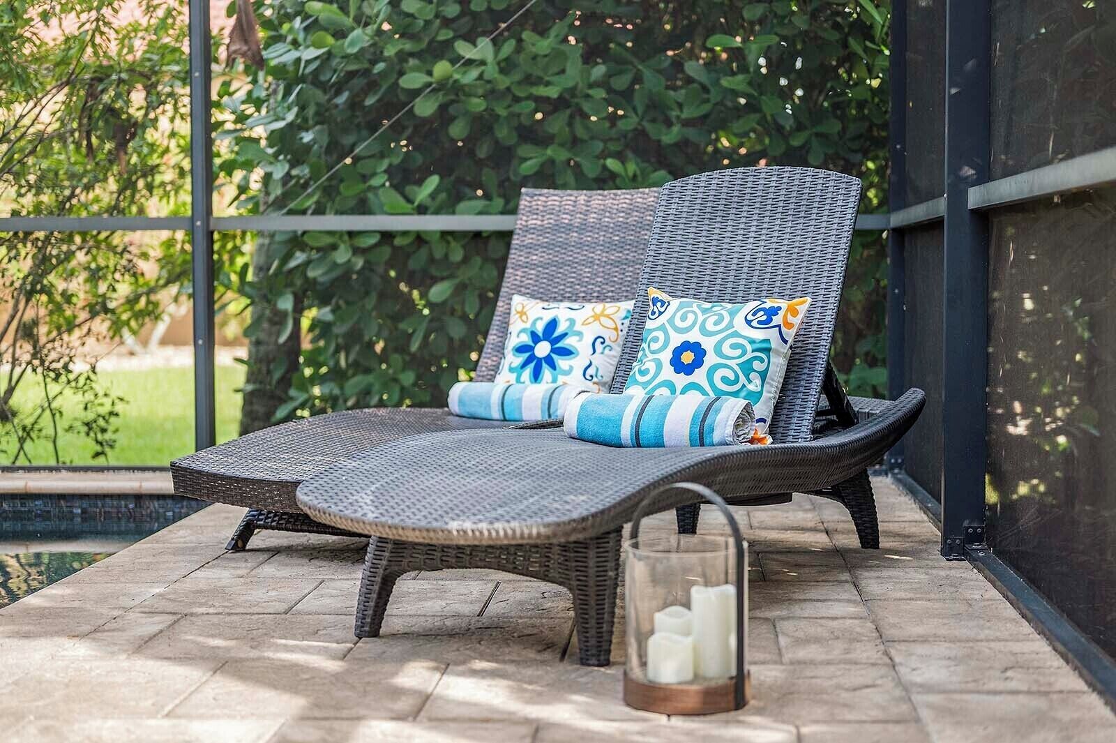Una silla de mimbre con cojines estampados en un patio de piedra.