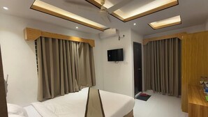 A hotel room with a bed, curtains, a television, and a ceiling fan. - Hotel Amin International Cox's Bazar (Cox's Bazar)