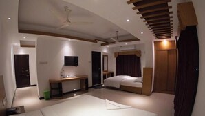 A modern hotel room with a large bed, a desk with a flat-screen TV, a ceiling fan, and a wooden ceiling design. - Hotel Amin International Cox's Bazar (Cox's Bazar)