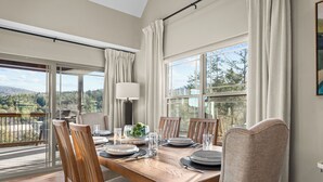 A dining area with a wooden table set for six, large windows, and a view of the outdoors. - *New* Sawyer's Rest - Hot Tub+ (Hollister)