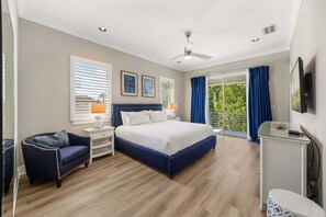 A bedroom with a large bed, a chair, a bedside table, a TV, and a window with curtains. - Bliss at Reunion-TT489 (Kissimmee)