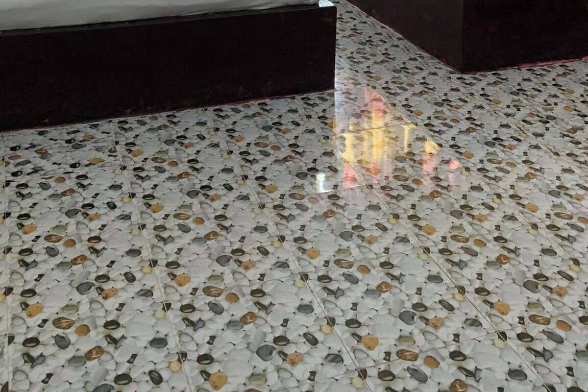 A hotel room with two beds, a mirror, and a tiled floor.