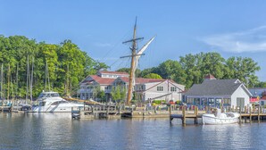 A marina with several boats docked, a large house with a red roof, and a smaller building with a flag. - Deercreek Retreat in South Haven, Spacious 4BR perfect for family getaways! (South Haven)