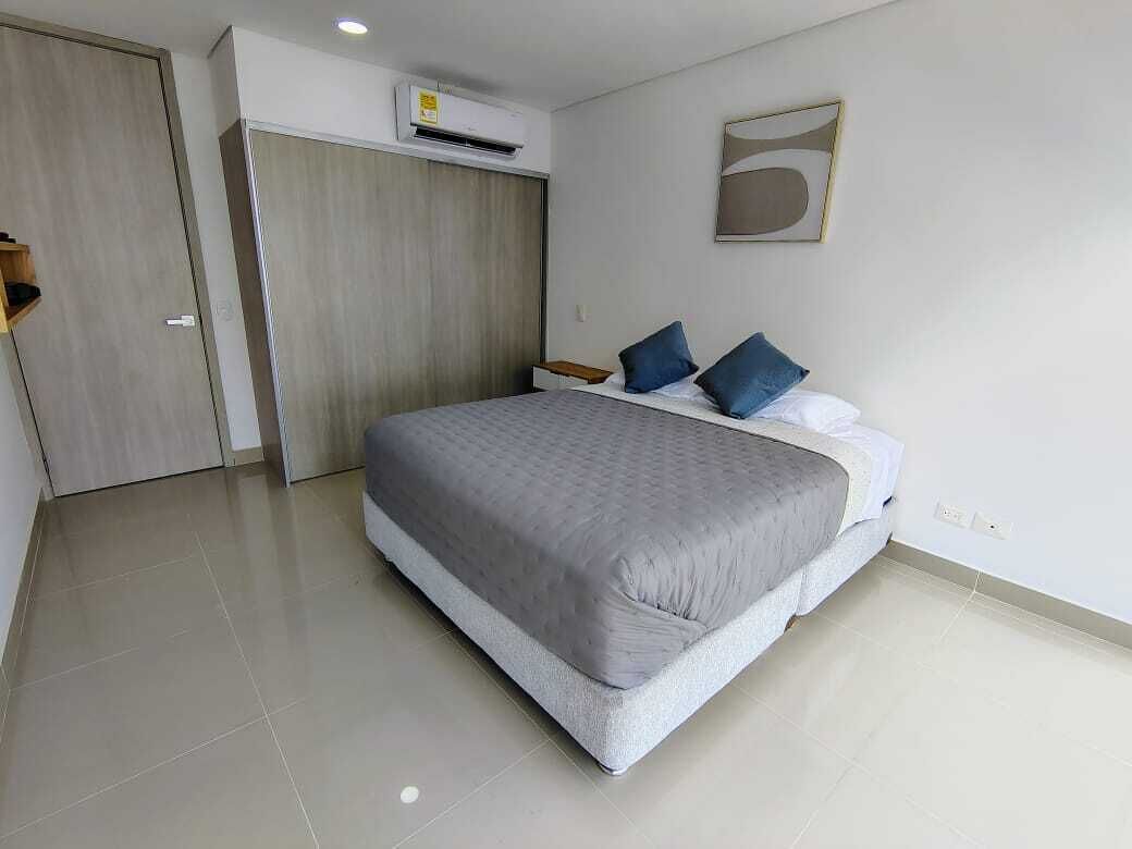 A bedroom with a bed, a wardrobe, a nightstand, and a wall-mounted air conditioner.