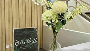 A reception desk with a framed sign reading "Brenthill" and a vase of white flowers. - Brenthill Baguio (Baguio)