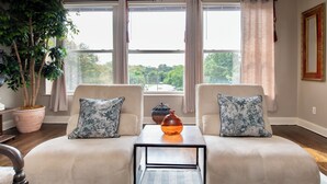 Una sala de estar con dos sofás, una mesa de centro, una planta en maceta y vistas al exterior.