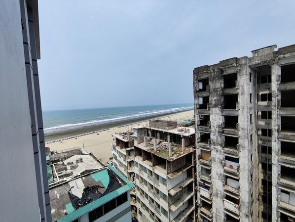 Un immeuble de grande hauteur, doté de nombreux étages, dont certains sont en construction. On aperçoit une plage au loin.