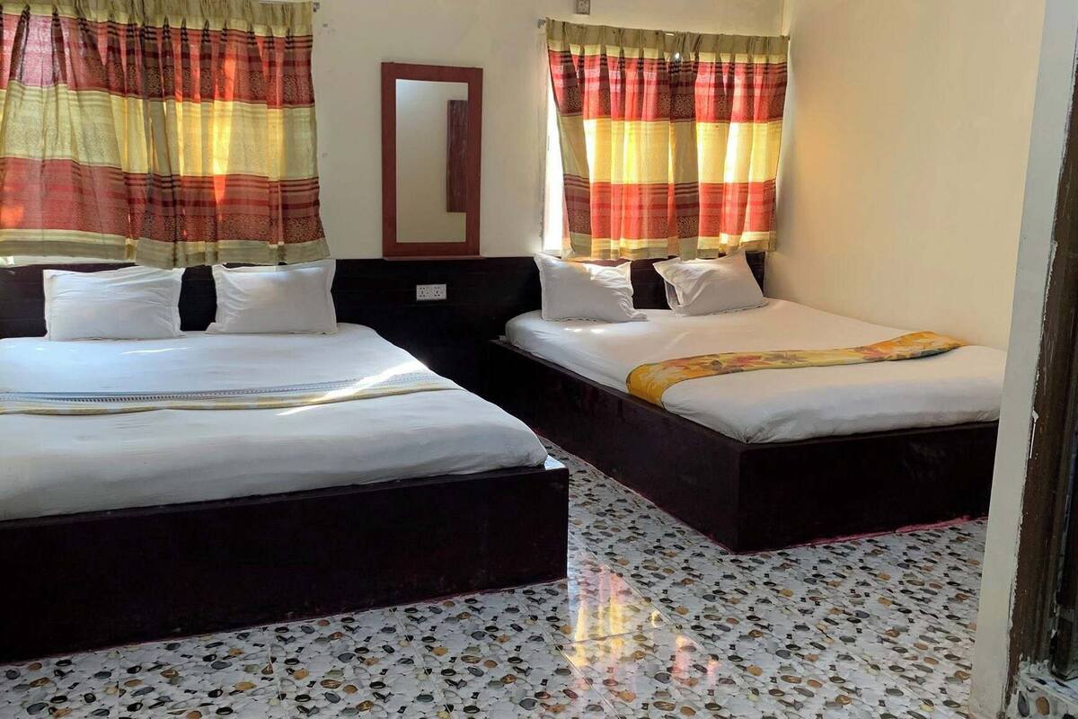 Ein Hotelzimmer mit zwei Betten, einem Spiegel und Vorhängen mit Muster.