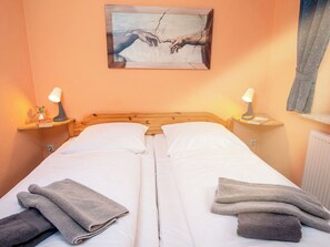 A double bed with white linens, two bedside tables with lamps, and a painting above the bed. - Apartment Mars by Interhome (Norden)