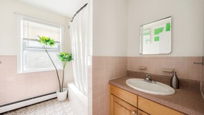 A bathroom with a window, a sink, a mirror, and a potted plant. - Luxury 3BR NY Home with Free Parking (White Plains)