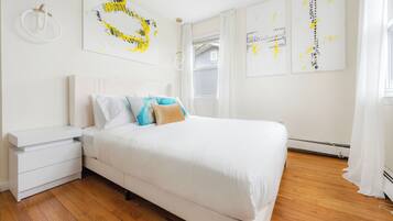 Um quarto com cama, mesa de cabeceira e luminária na parede.