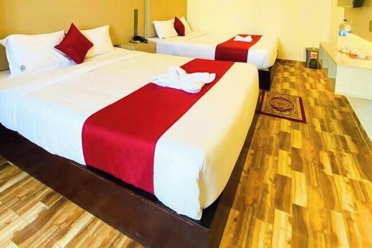 Une chambre d’hôtel avec deux lits, un plancher en bois et un petit bureau avec une chaise.
