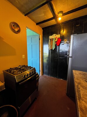 A kitchen with a gas stove, a refrigerator, and a door leading to another room. - Amazing Ocean view guest house, just next to a monkey trail (Guanacaste Province)
