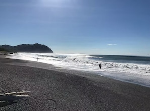 A beach with pebbly shore, waves, and a distant mountain. - Amazing Ocean view guest house, just next to a monkey trail (Guanacaste Province)