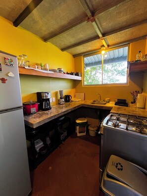 A compact kitchen with a refrigerator, stove, sink, and a window providing natural light. - Amazing Ocean view guest house, just next to a monkey trail (Guanacaste Province)