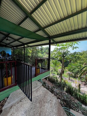 A covered outdoor area with a metal roof, a green railing, and a view of lush greenery. - Amazing Ocean view guest house, just next to a monkey trail (Guanacaste Province)