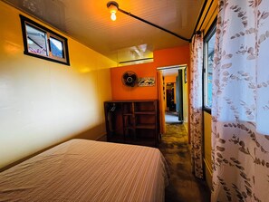 A room with a bed, a fan, a window with curtains, and a door leading to another room. - Amazing Ocean view guest house, just next to a monkey trail (Guanacaste Province)