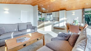 A modern living room with a wooden ceiling, a grey sofa, a wooden coffee table, and a kitchen area in the background. - Field View 2 bed-No pets-Hornbeam - sleeps 6 guests  in 2 bedrooms (Eye)