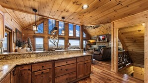 Una cocina amplia con armarios de madera, encimera de granito y ventanas grandes que ofrecen vistas al exterior.