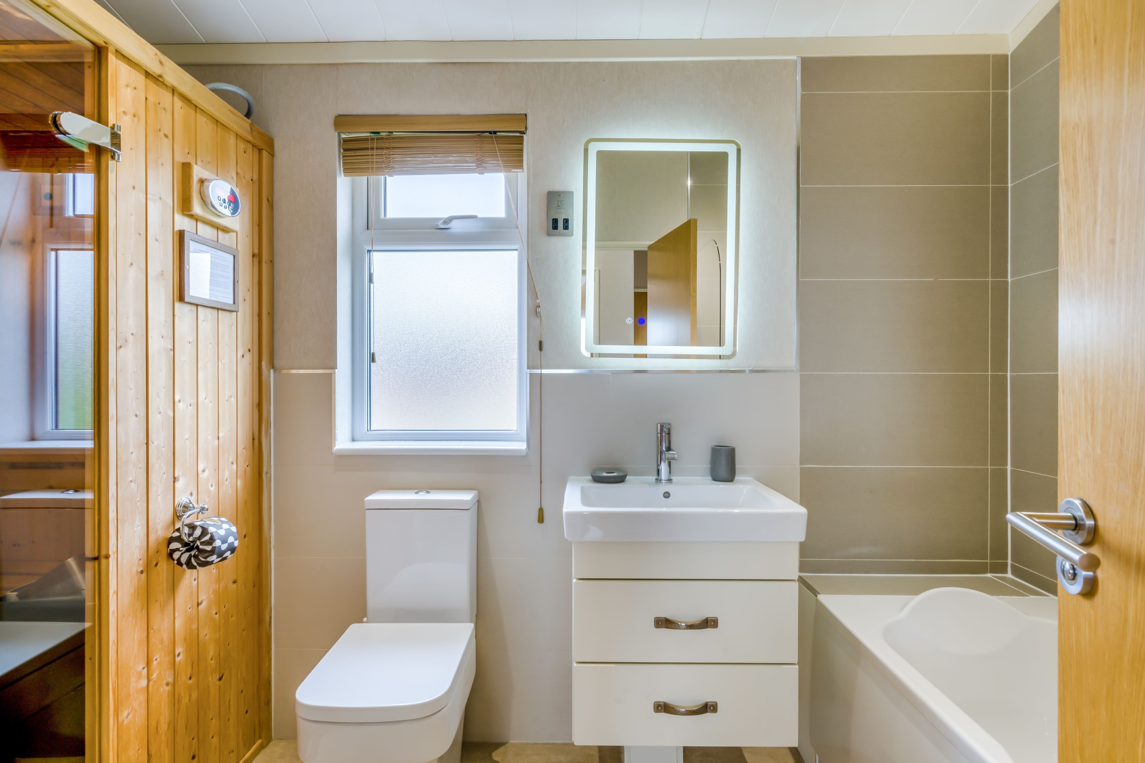 A bathroom with a wooden door, a toilet, a sink with a mirror, and a bathtub.