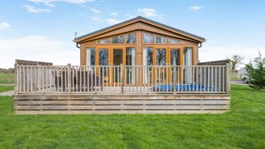 Een houten chalet met balkon, omringd door een houten hek, gelegen in een grasrijke omgeving.