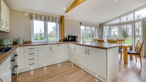 Een moderne keuken met witte kastjes, een houten aanrecht en een eethoek met houten stoelen.