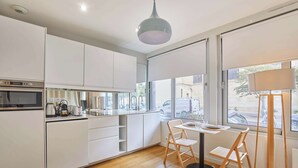 A modern kitchen with white cabinets, a built-in oven, and a dining area with a table and chairs. - Modern Suite Invalides Tour Eiffel (Paris)