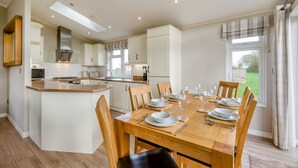 Een moderne keuken met een eethoek, houten meubels en uitzicht op de omgeving.